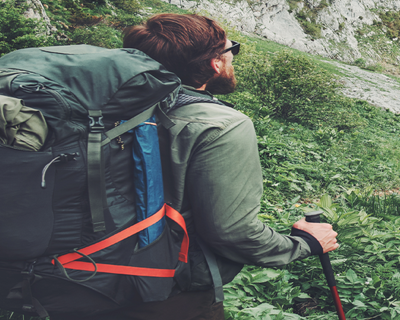 Coiled lanyard stretched to secure equipment to a rucksack outdoors